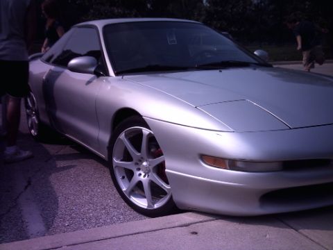 1995 Ford Probe - A silver coupe is parked on the street, custom wheels and visible red brake calipers.