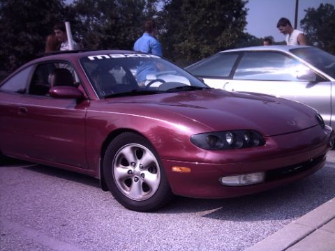 1995 Ford Probe - Maroon Mazda MX-6 coupe with a 'mazda' banner on the windshield is parked outdoors.