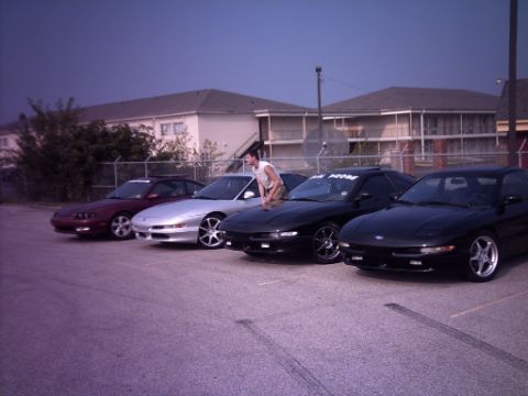 1995 Ford Probe - A line of Ford Probes are parked in a lot under a dusky sky.