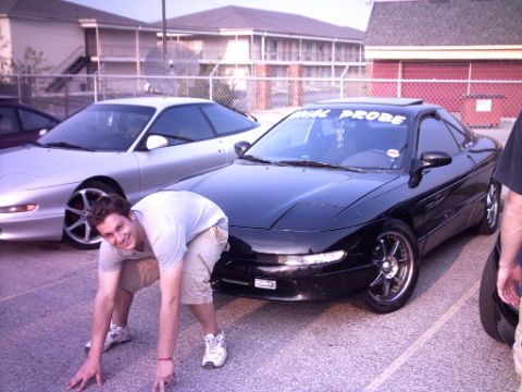 1995 Ford Probe - Two Ford Probes are parked, with a man in the foreground. One car has a banner on its windshield.