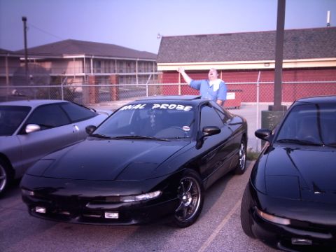 1995 Ford Probe - A black Ford Probe is parked in a lot with another Probe, and a person is standing in the sunroof.