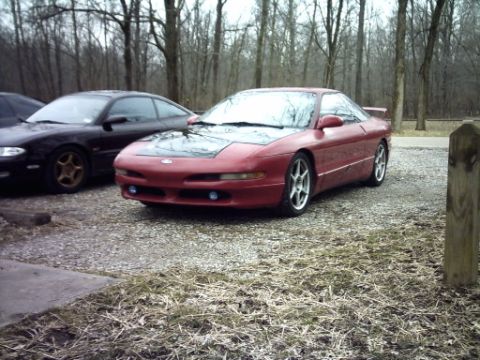 1995 Ford Probe - A red 1995 Ford Probe is parked in a gravel lot, with another vehicle visible to its left.