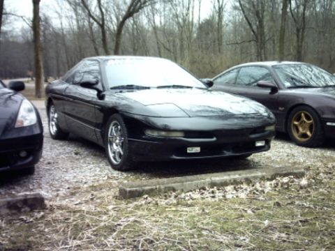 1995 Ford Probe - A black 1995 Ford Probe is parked in a lot with other vehicles, showing its distinctive body style.