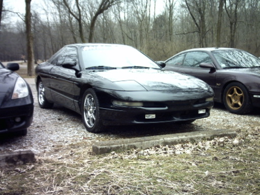 Black 1995 Ford Probe with chrome wheels, parked outdoors