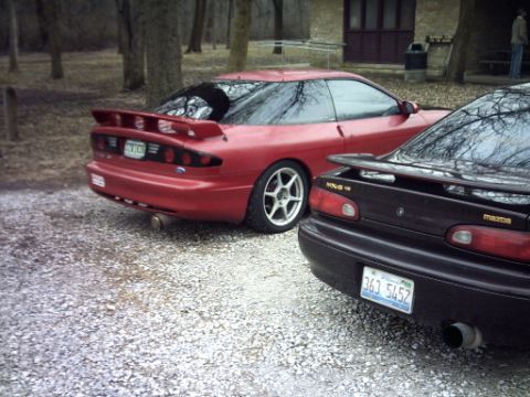 1995 Ford Probe - Two sporty coupes, a red 1995 Ford Probe and a black Mazda MX-3, are parked side-by-side in an outdoor setting.