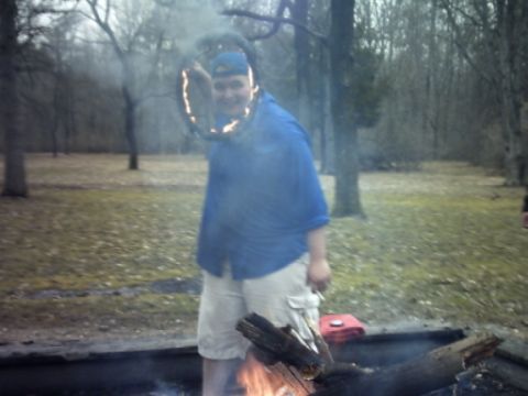 1995 Ford Probe - A person holds a flaming tire rim in a wooded area with a campfire in the foreground.