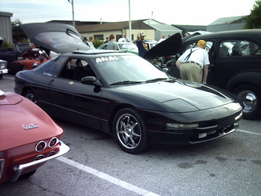 Black 1995 Ford Probe with its rear hatch open, parked next to a red classic car
