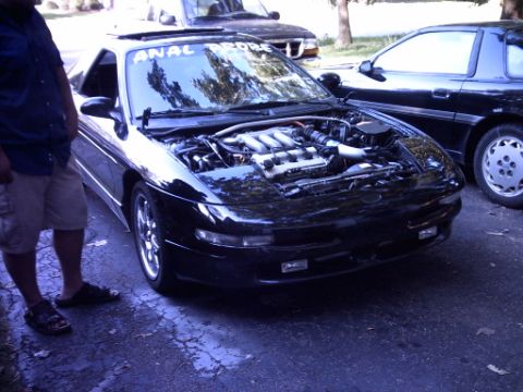1995 Ford Probe - A black sports car's engine is visible with the hood open, parked on an asphalt surface.