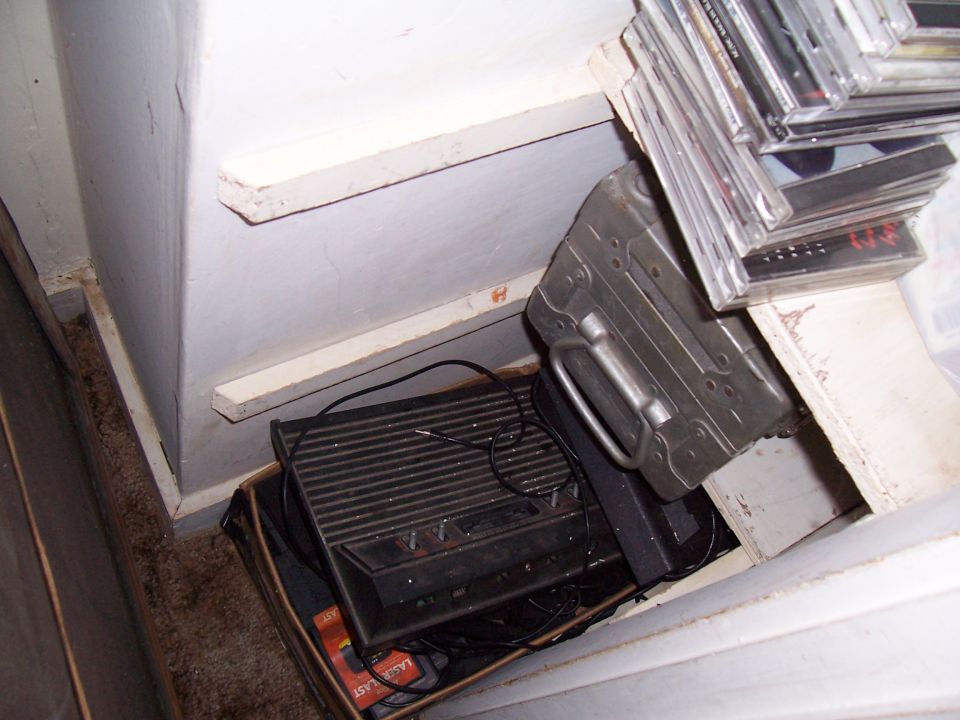 Old video game console and stack of CDs in a corner