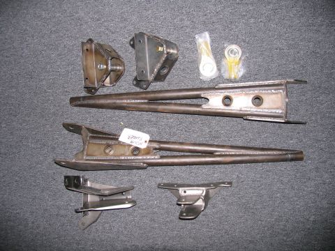 1984 Ford Bronco - Various suspension linkage components and mounting brackets are laid out on a gray surface.
