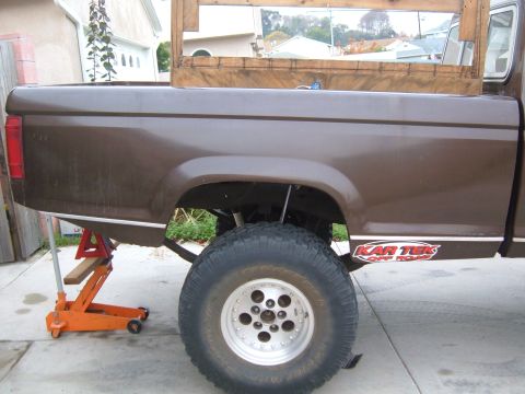 1985 Ford Ranger - Side view of a 1985 Ford Ranger pickup truck bed, showing the rear wheel and suspension.