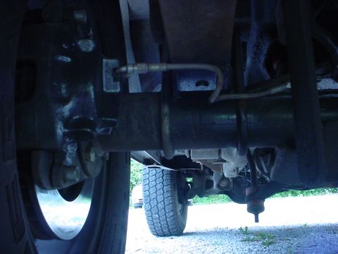 1983 Ford Bronco - Close-up view of the undercarriage, focusing on the rear axle and suspension system of a vehicle.