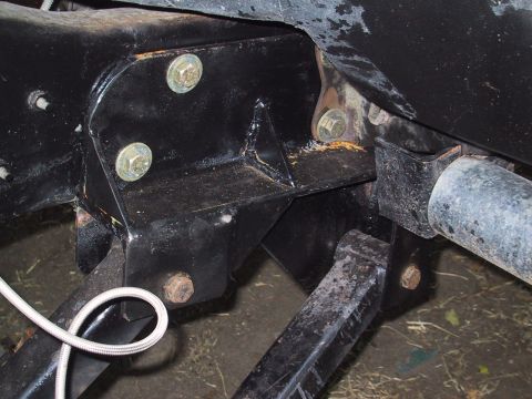 1990 Ford Bronco - Close-up view of vehicle frame and suspension components, with visible bolts and a braided hose.