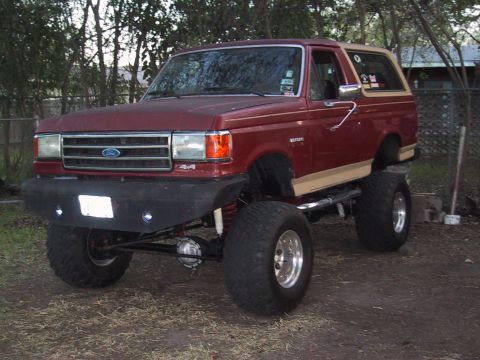 1990 Ford Bronco - This modified Ford Bronco features a significant lift kit and oversized tires, giving it an aggressive stance.