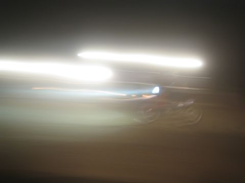 1990 Ford Bronco - Bright streaked headlights and motion blur from a fast-moving vehicle photographed at night create abstract light trails.