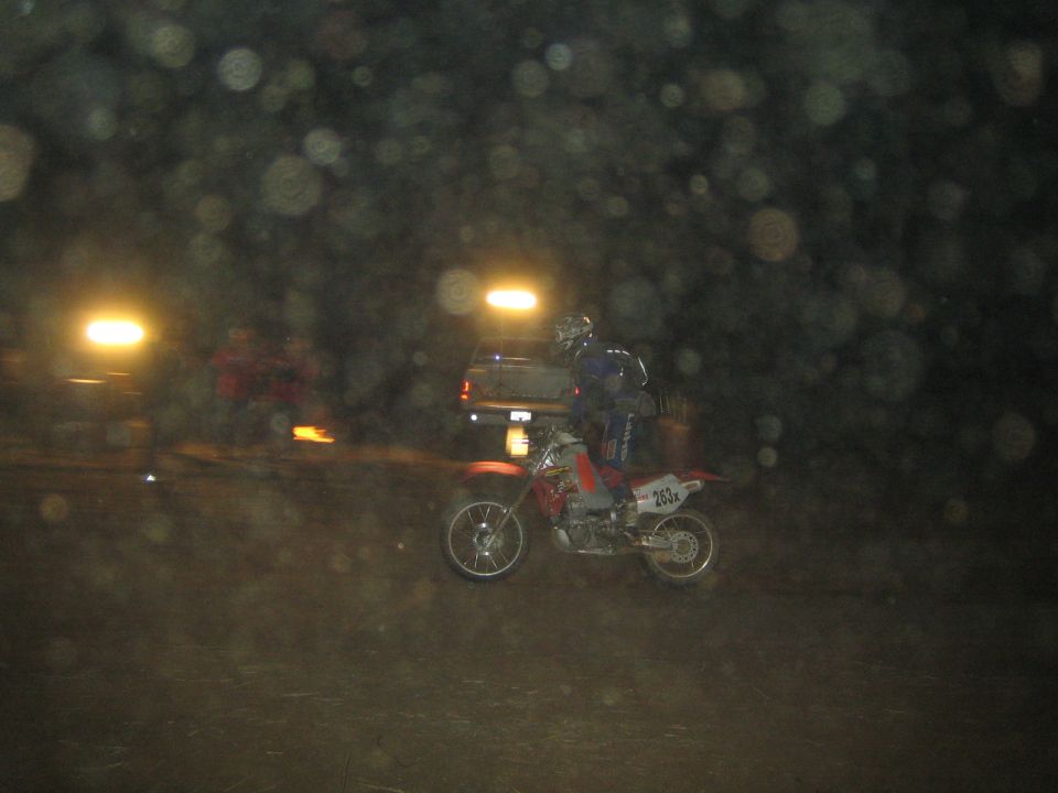 Rider on a red dirt bike numbered 263 at a night off-road event
