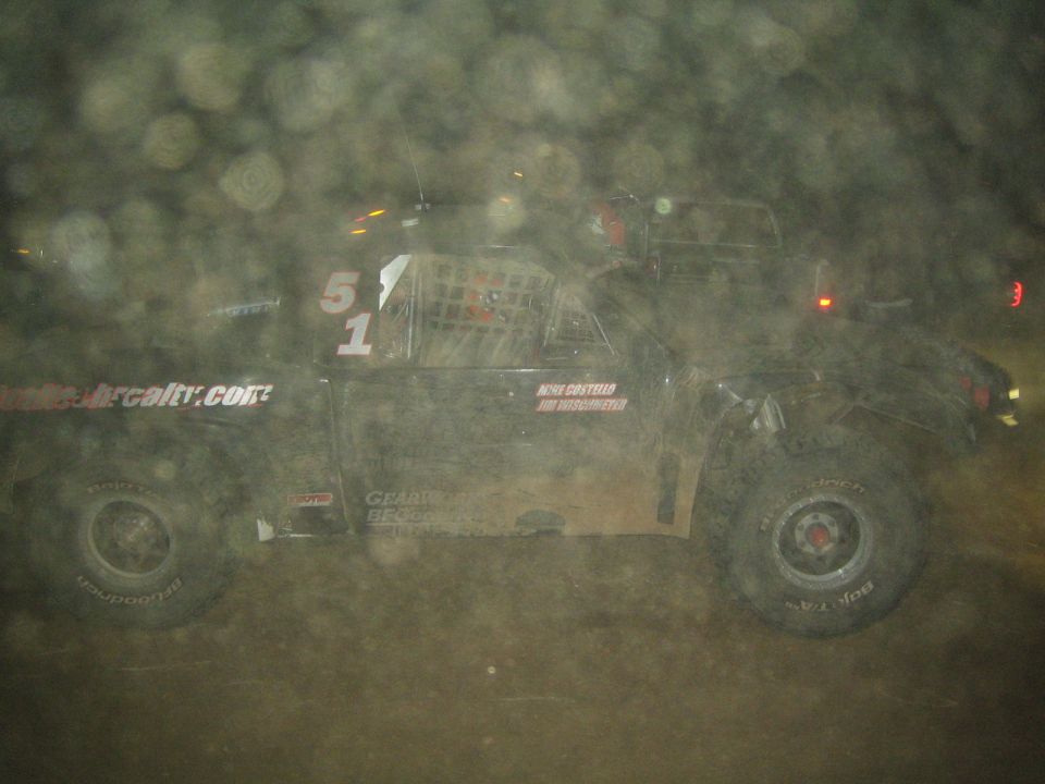 Black off-road race truck number 51 with website decals racing at night