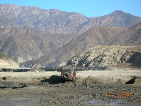 1985 Ford Bronco - An orange Jeep navigates a muddy terrain with a mountainous backdrop, dated November 27, 2005.