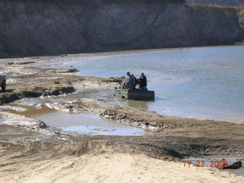 1985 Ford Bronco - A green pickup truck is stuck in muddy water with several people in its bed, as seen on November 27, 2005.