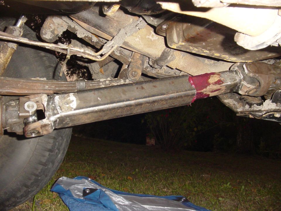 close-up of vehicle's driveshaft and suspension components, with grease visible on the driveshaft