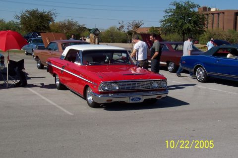 1969 Ford Ranchero - A red and white 1964 Ford convertible is parked at an outdoor car meet with other vehicles.