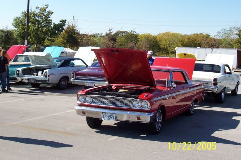 1969 Ford Ranchero - A red 1964 Ford Fairlane 500 is parked with its hood open at an outdoor car meet, alongside other vehicles.