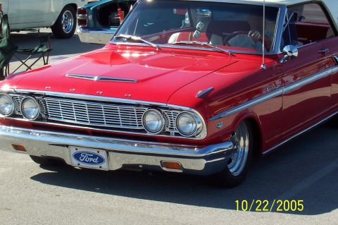 1969 Ford Ranchero - A red 1963 Ford Fairlane with a white roof is parked outdoors, with other vehicles visible in the background.