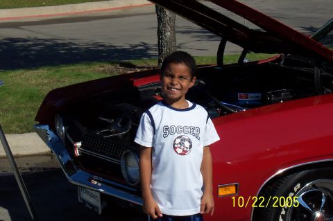 1969 Ford Ranchero - A young boy poses in front of a classic red Ford Torino GT at an outdoor car event.