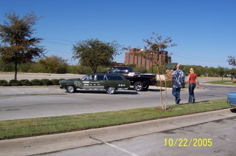 1969 Ford Ranchero - A unique green station wagon with custom graphics is seen next to a pickup truck, with two people walking in the background.