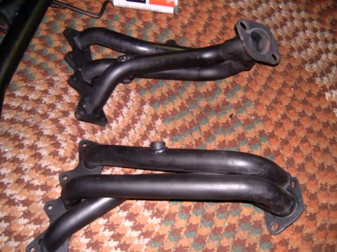 1994 Ford Probe - A pair of black exhaust headers are shown on a patterned carpet, likely for a vehicle.