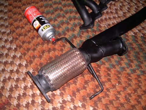 1994 Ford Probe - Exhaust pipe part with flex pipe and a spray can on a carpeted surface.