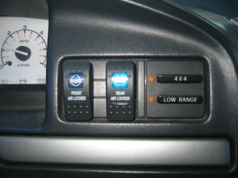 1992 Ford Bronco - Close-up of auxiliary switches and gauges on a vehicle's dashboard, including air locker and drivetrain controls.