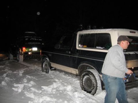 1992 Ford Bronco - Two SUVs are parked in the snow at night, with a man standing next to the Bronco.