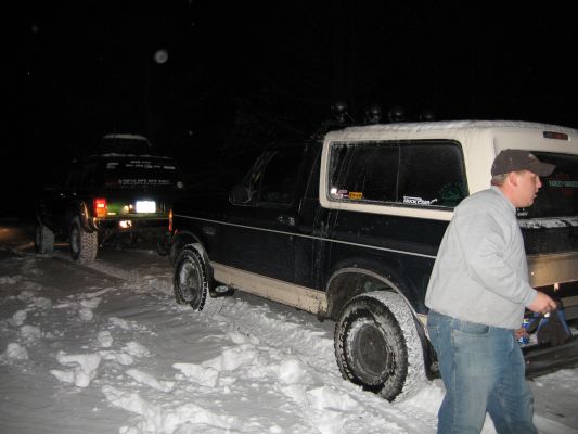 1992 Ford Bronco and another SUV parked in snow at night