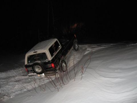 1992 Ford Bronco - A 1992 Ford Bronco is stuck on a snow-covered hill at night, with its tires off the ground.