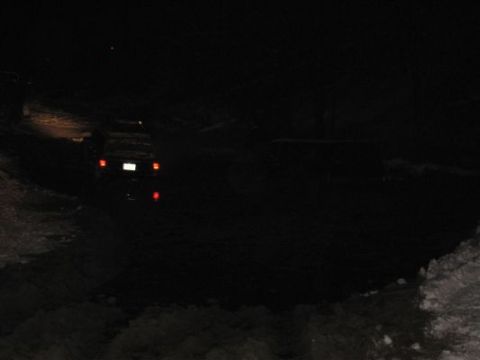 1992 Ford Bronco - A dark SUV is seen from the rear at night, with its license plate and taillights illuminated.