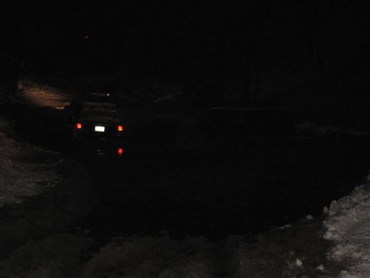 Dark SUV with illuminated license plate and red taillights, viewed from rear at night