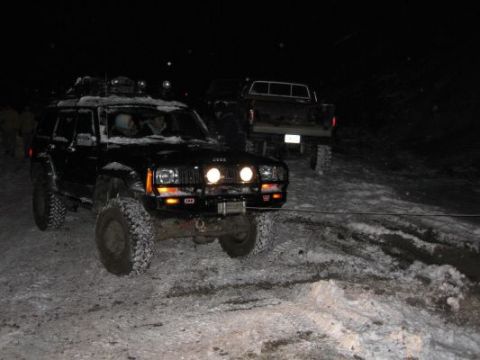 1992 Ford Bronco - Two off-road vehicles are stuck in the snow at night, with one being a Jeep Cherokee XJ.