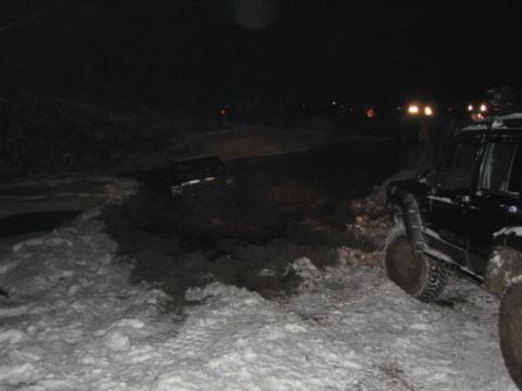 1992 Ford Bronco - Off-road vehicles navigate a snowy and muddy terrain at night.