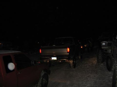 1992 Ford Bronco - Several trucks and SUVs are parked together in a lot at night.