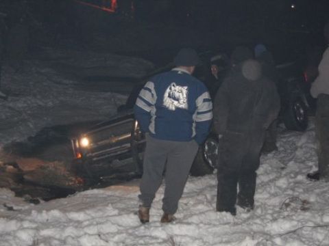 1992 Ford Bronco - A truck is stuck in a snowy ditch, with several people standing around it.