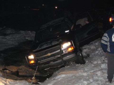 1992 Ford Bronco - A black pickup truck appears stuck in a snowy ditch at night.