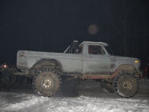 1992 Ford Bronco - A heavily modified pickup truck with large off-road tires is shown in a snowy environment at night.