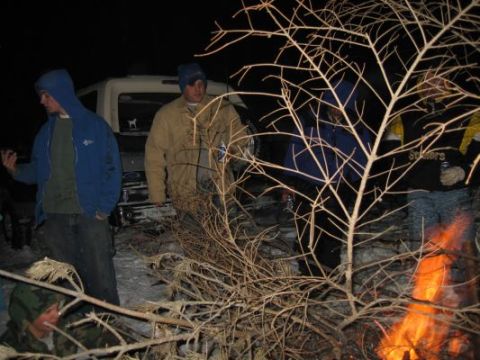 1992 Ford Bronco - A group of people stand around a 1992 Ford Bronco at night, with a fire burning in the foreground.