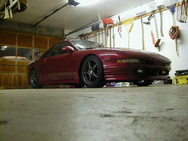 Red 1994 Ford Probe parked in a garage with tools on the wall
