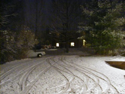 1994 Ford Probe - A white car sits in a snow-covered driveway at night, with tire tracks visible in the snow.