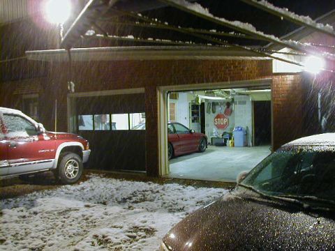 1994 Ford Probe - Two vehicles are visible outside a garage during a snowfall.