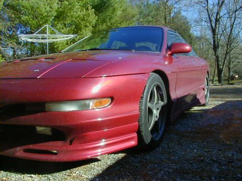1994 Ford Probe - A red 1994 Ford Probe is parked on a gravel surface with trees in the background.