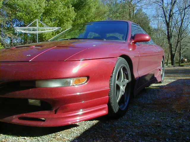 Red 1994 Ford Probe coupe, front 3/4 view, parked outdoors on gravel