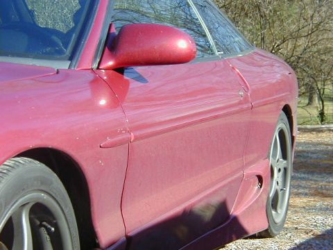 1994 Ford Probe - Side view of a red 1994 Ford Probe, focusing on the door and front fender.